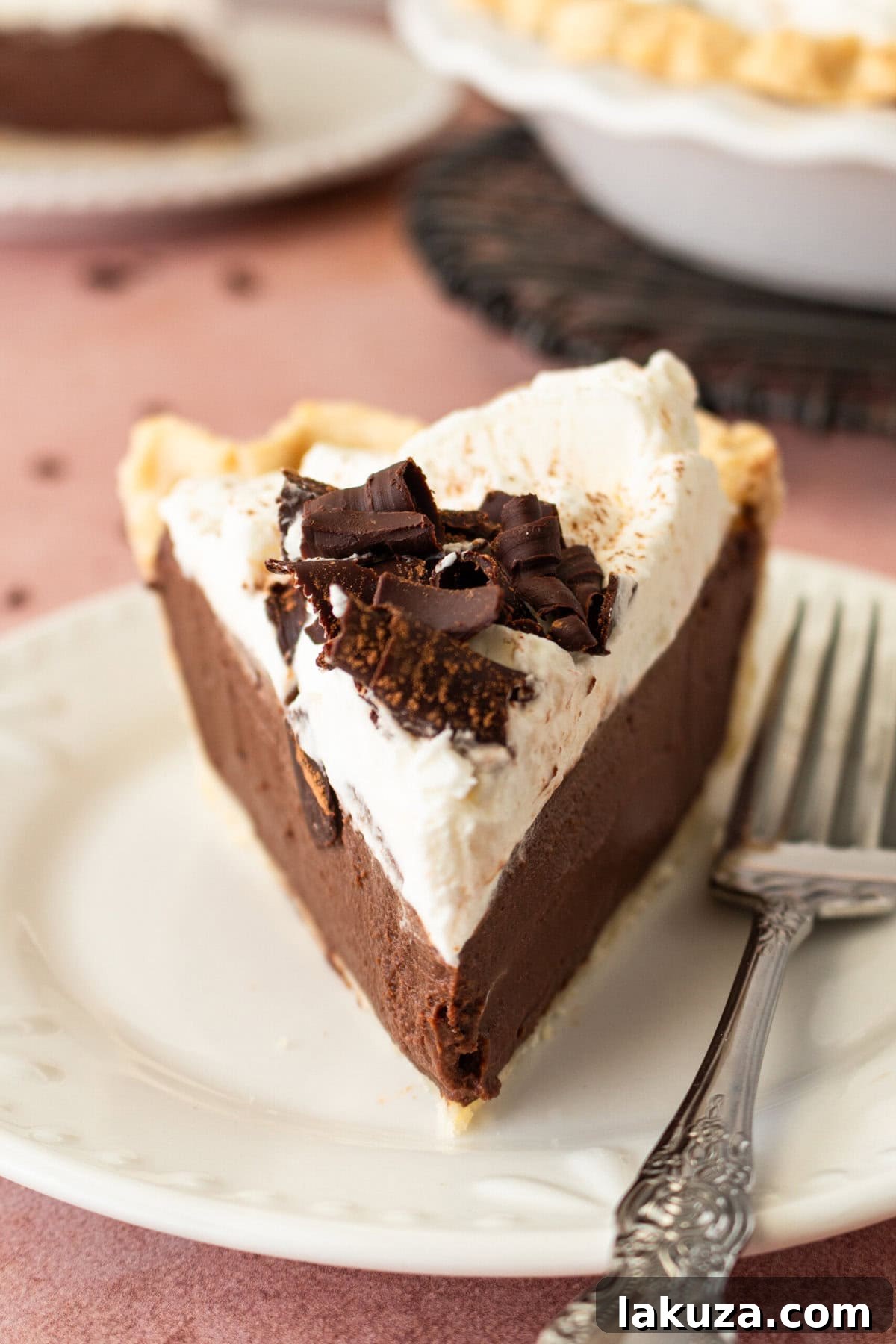 Close-up of a slice of the best Chocolate Cream Pie, showing layers of flaky crust, dark chocolate custard, and whipped cream.