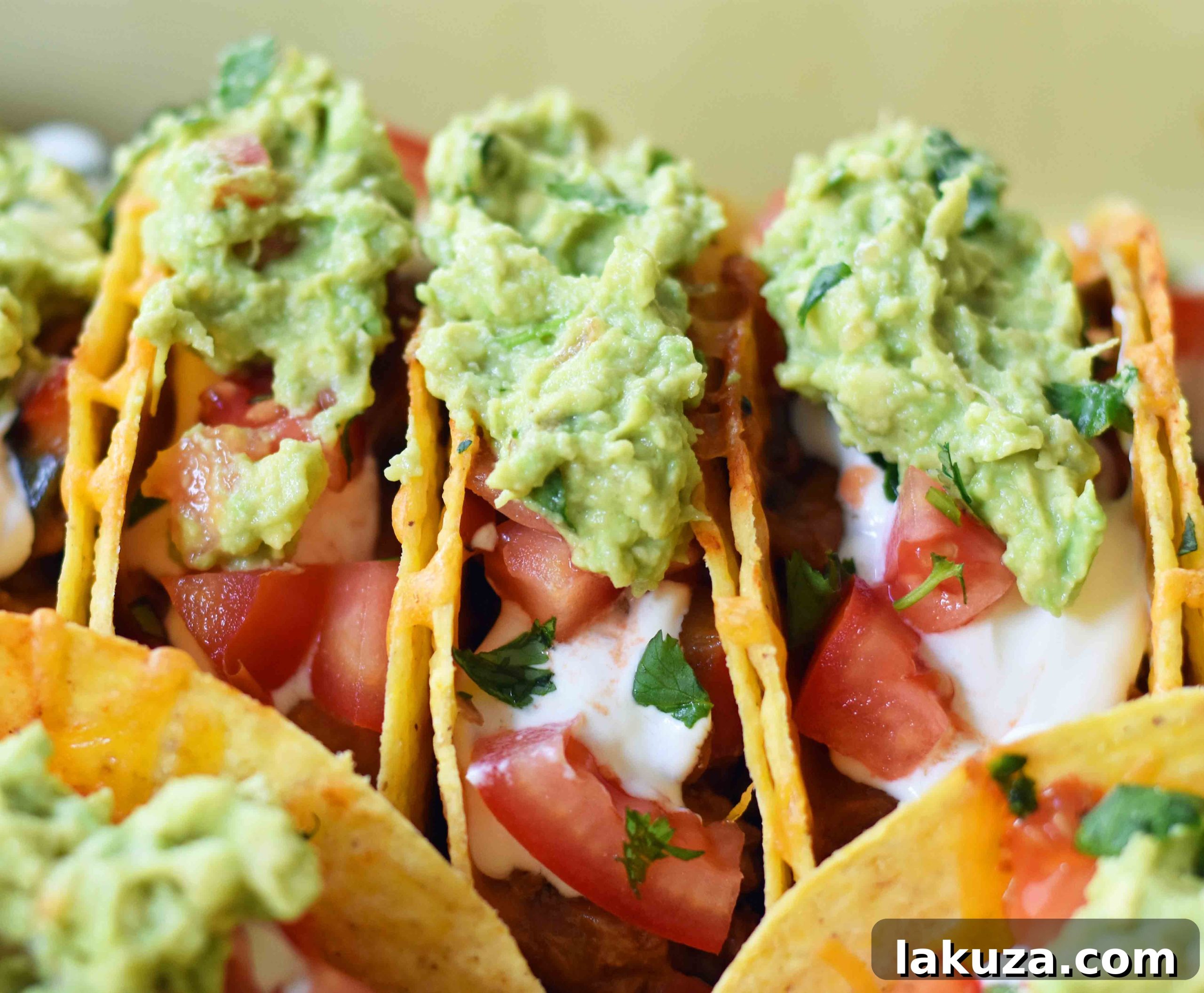 Assembling oven-baked beef tacos in flat-bottomed shells, ready for the oven.