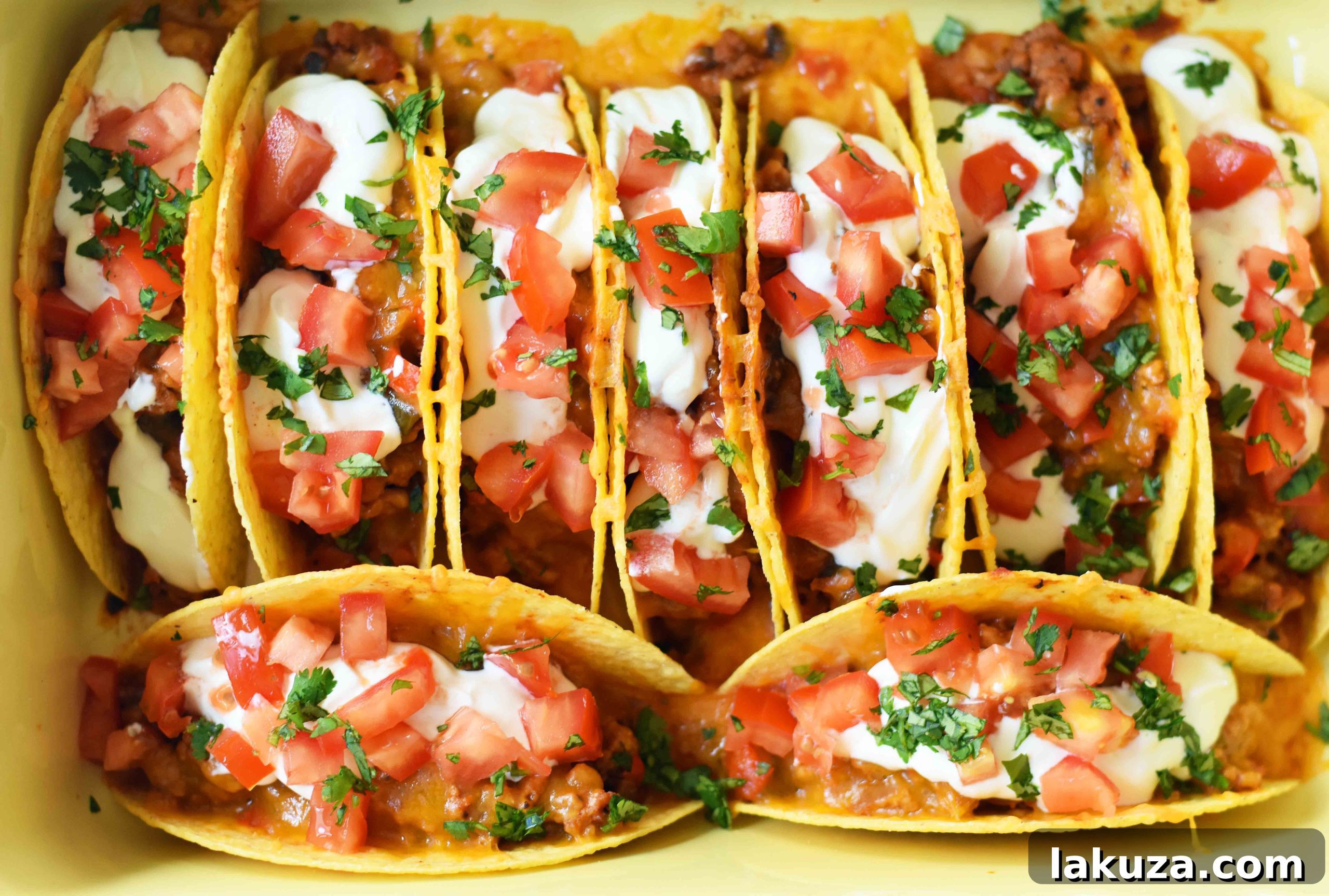 A serving of crispy oven-baked beef tacos, garnished with fresh salsa, sour cream, and cilantro.
