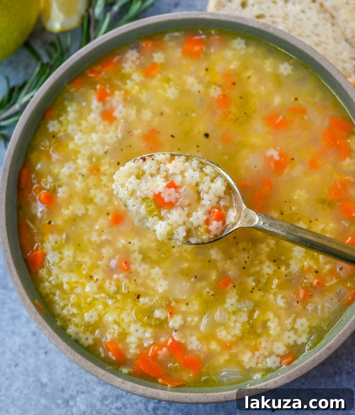 Heartwarming Italian Pastina Soup 5 A bowl of Pastina Soup garnished with fresh herbs and a slice of rustic bread on the side.
