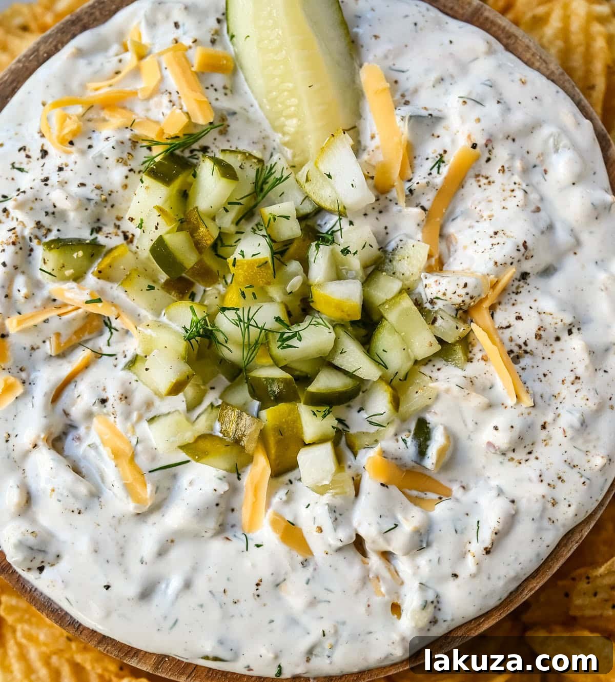 Tangy Dill Delight 4 A bowl of creamy dill pickle dip surrounded by various dippers on a wooden board.