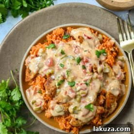 Queso Smothered Chicken, a comforting meal with juicy chicken, Spanish rice, and creamy homemade queso sauce.