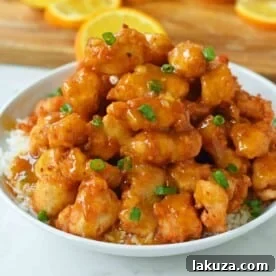 Crispy homemade Chinese Orange Chicken with a sweet and tangy orange sauce, better than any takeout, served with rice and green onions.