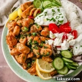 High-protein, low-carb Greek Chicken Bowls with grilled lemon chicken, fresh vegetables, feta, and tzatziki.