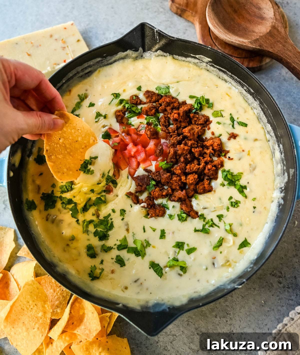 Ultimate Creamy Queso Dip 3 A close-up view of irresistibly smooth, white queso dip clinging to a tortilla chip, showcasing its perfect texture.