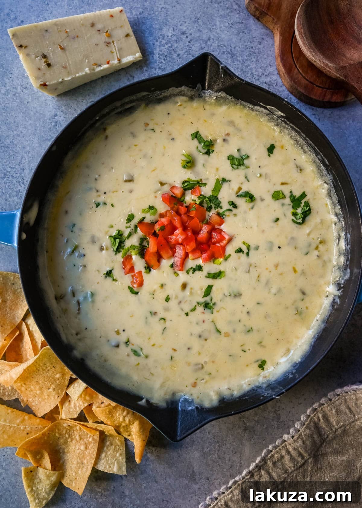 Ultimate Creamy Queso Dip 4 Three small bowls of white queso dip, each topped with different garnishes like cilantro and diced tomatoes.