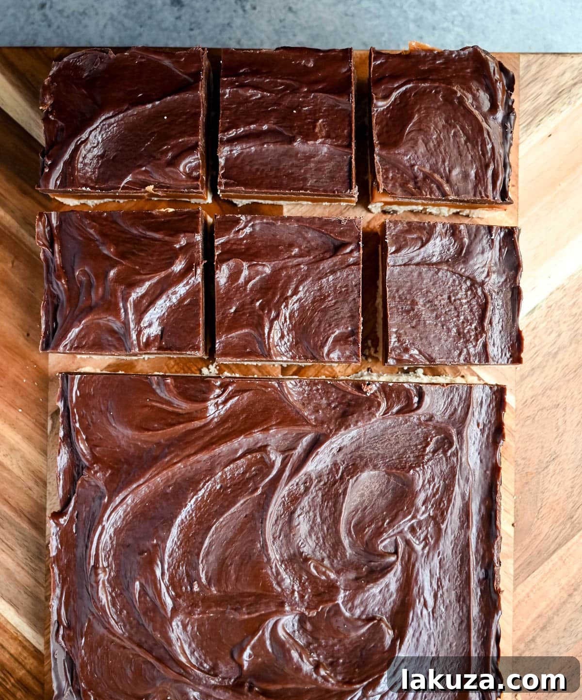 Decadent Millionaire Bars 6 A person using a warmed, sharp knife to cut chilled Millionaire Bars into neat squares.