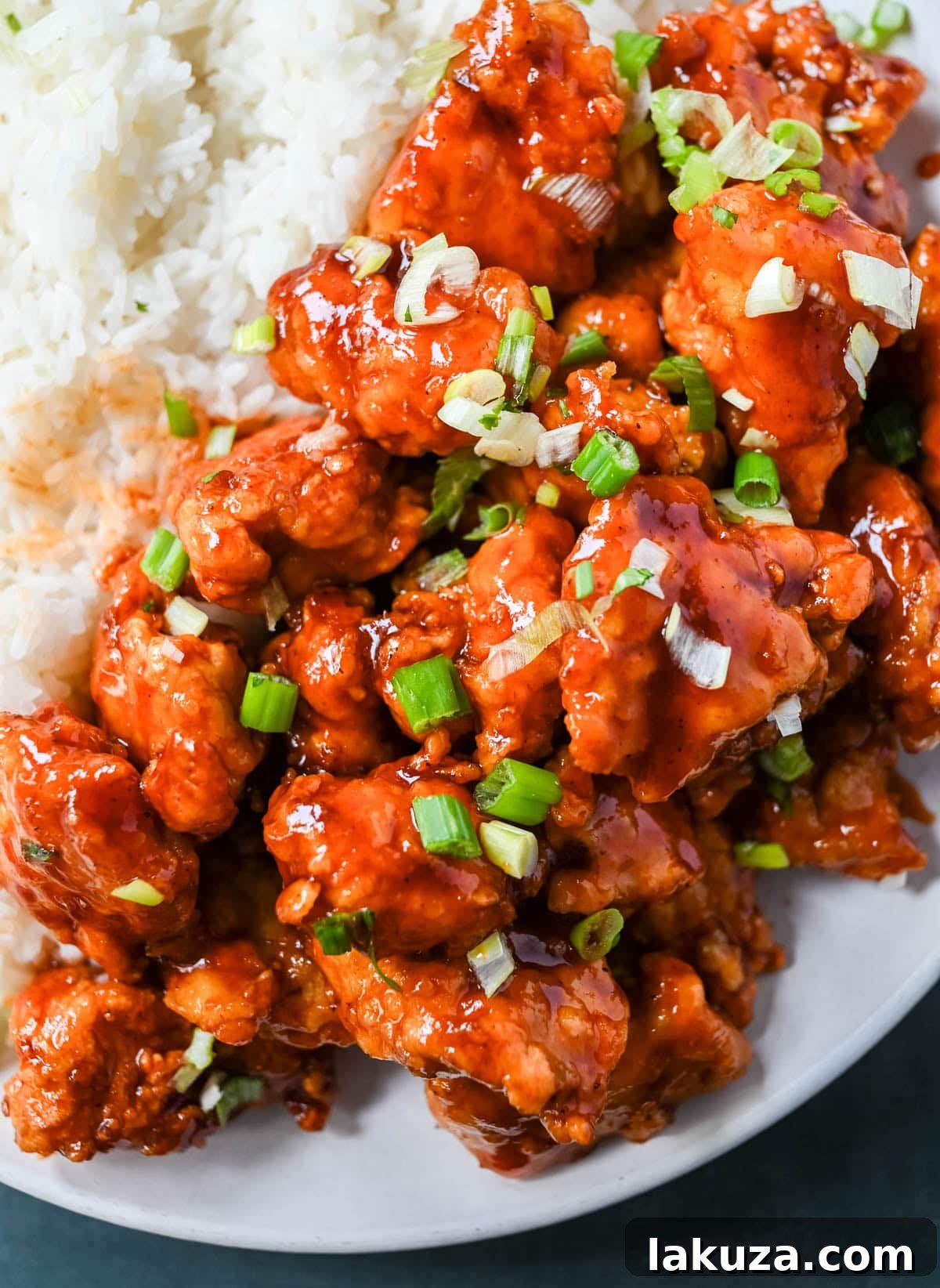 Sticky Honey Sriracha Chicken 2 Crispy homemade Honey Sriracha Chicken pieces coated in a glossy, sticky sweet and spicy glaze, ready to be served over rice.