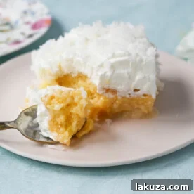 Coconut Poke Cake made with a baked cake mix, filled with cream of coconut and sweetened condensed milk, topped with whipped cream and coconut.