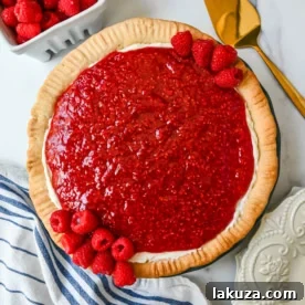 Homemade Raspberry Cream Pie with a sweet vanilla cream cheese cheesecake filling, topped with a homemade raspberry sauce, all in a buttery, flaky homemade crust.