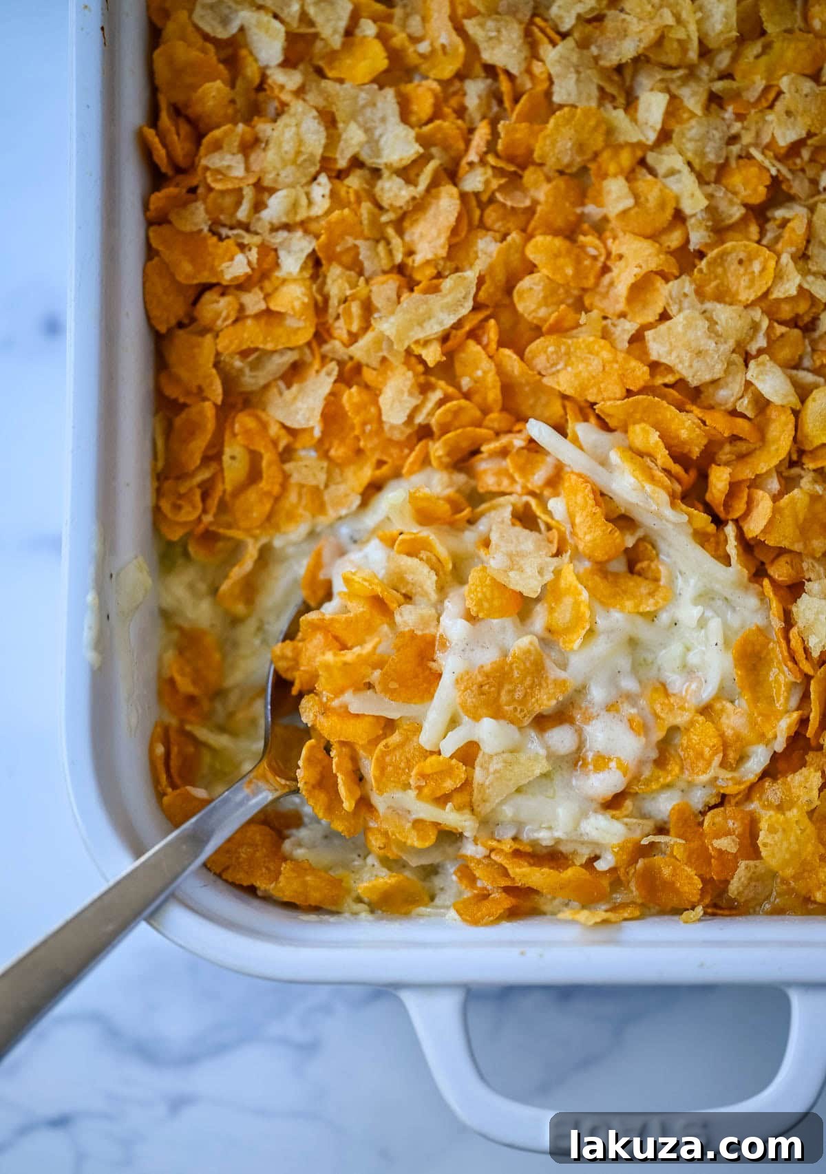 Hearty Cheesy Potato Casserole 4 A serving spoon scooping out a generous portion of warm Funeral Potatoes, showcasing the delightful creamy texture and melted cheese.