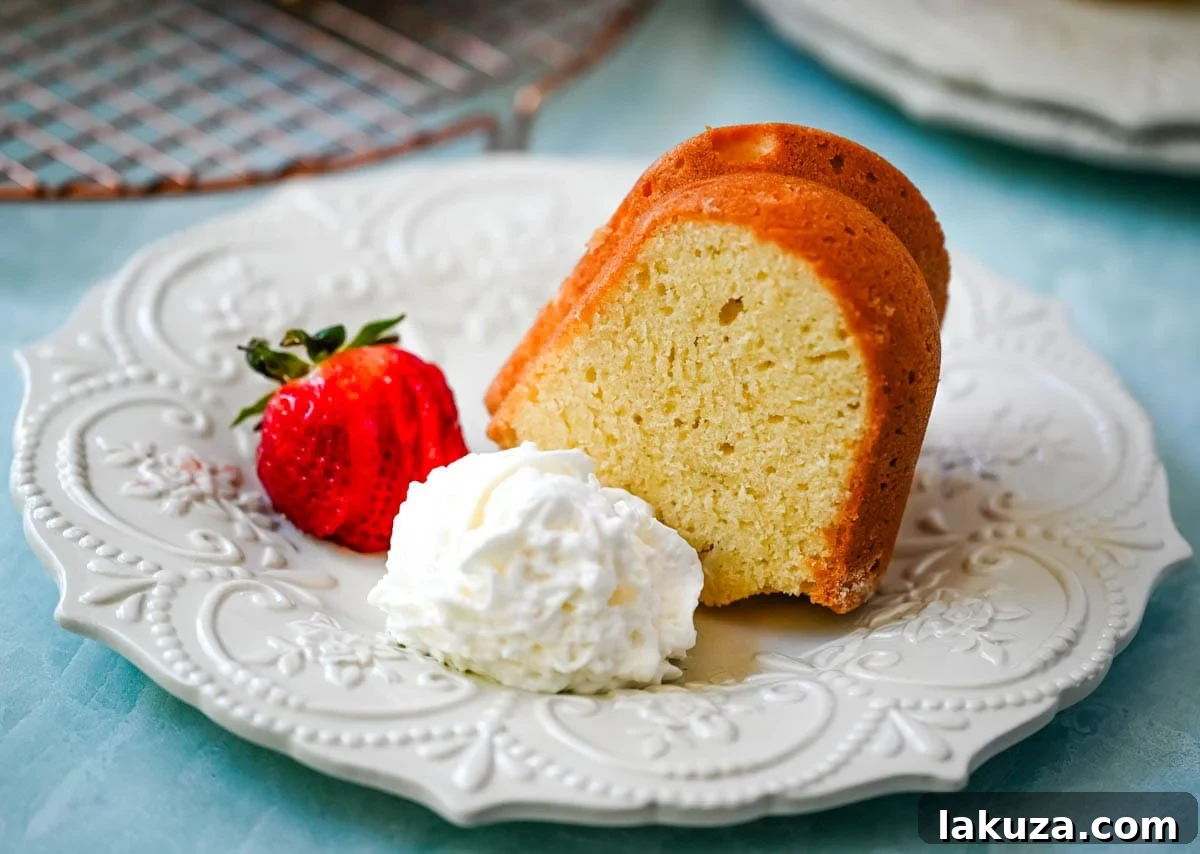 A slice of sour cream pound cake topped with fresh berries and a dusting of powdered sugar.