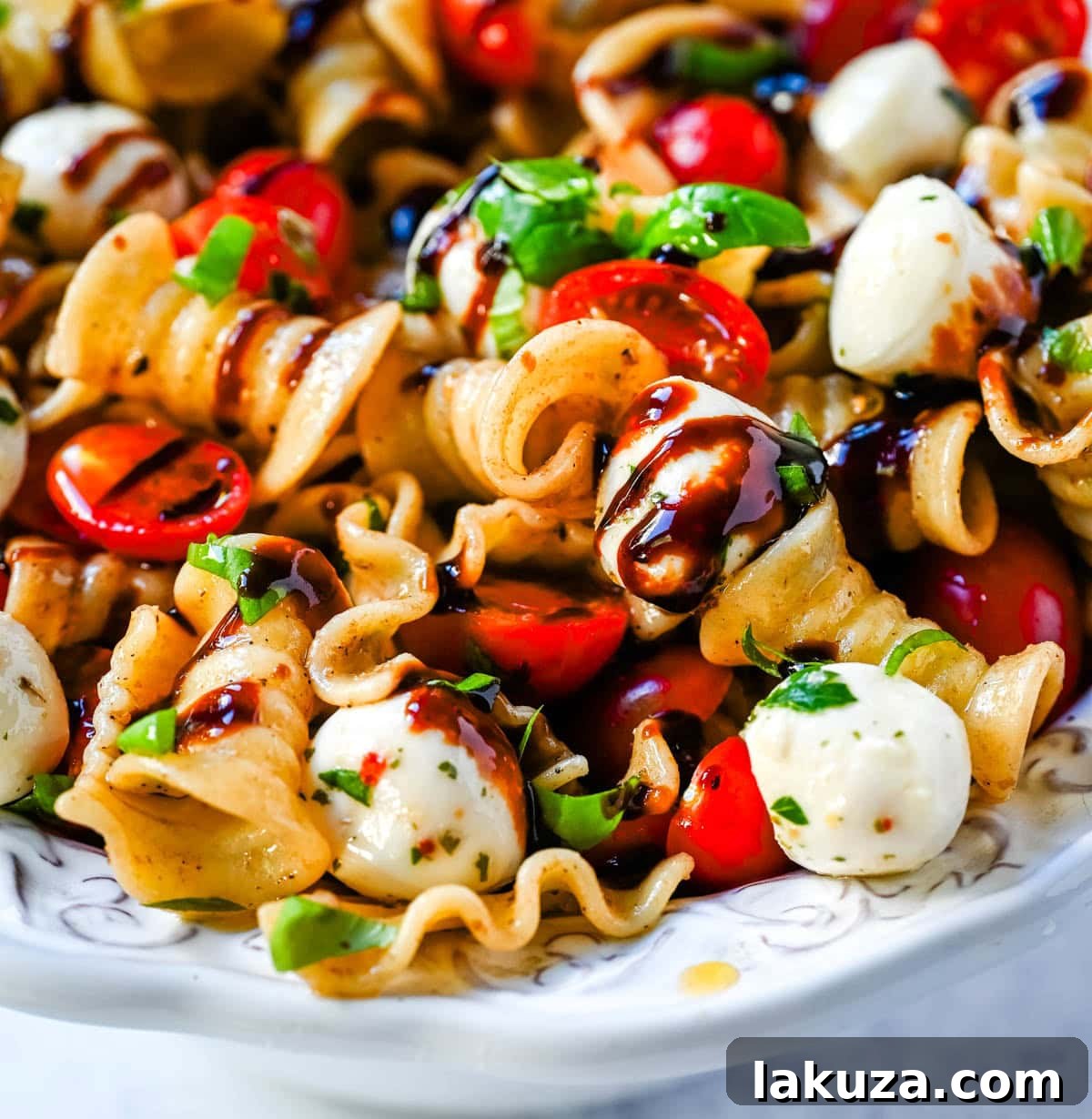 A bowl of freshly made Caprese pasta salad, ready to be served, showcasing the beautiful colors of red tomatoes, white mozzarella, and green basil.