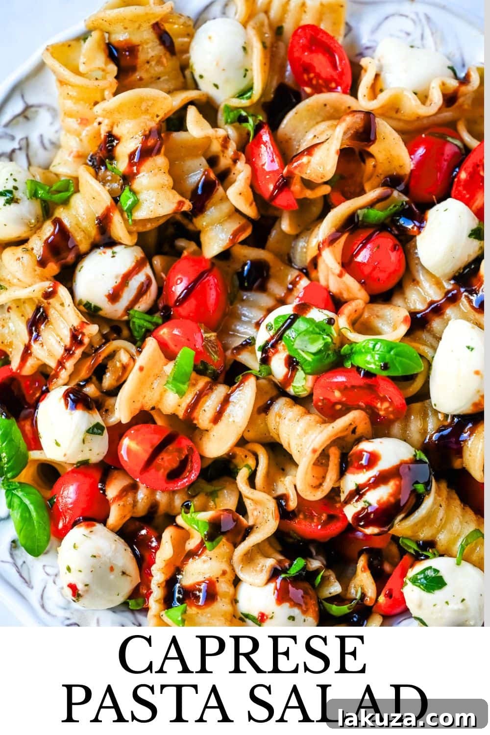Caprese pasta salad served in a elegant bowl, garnished with fresh basil leaves.