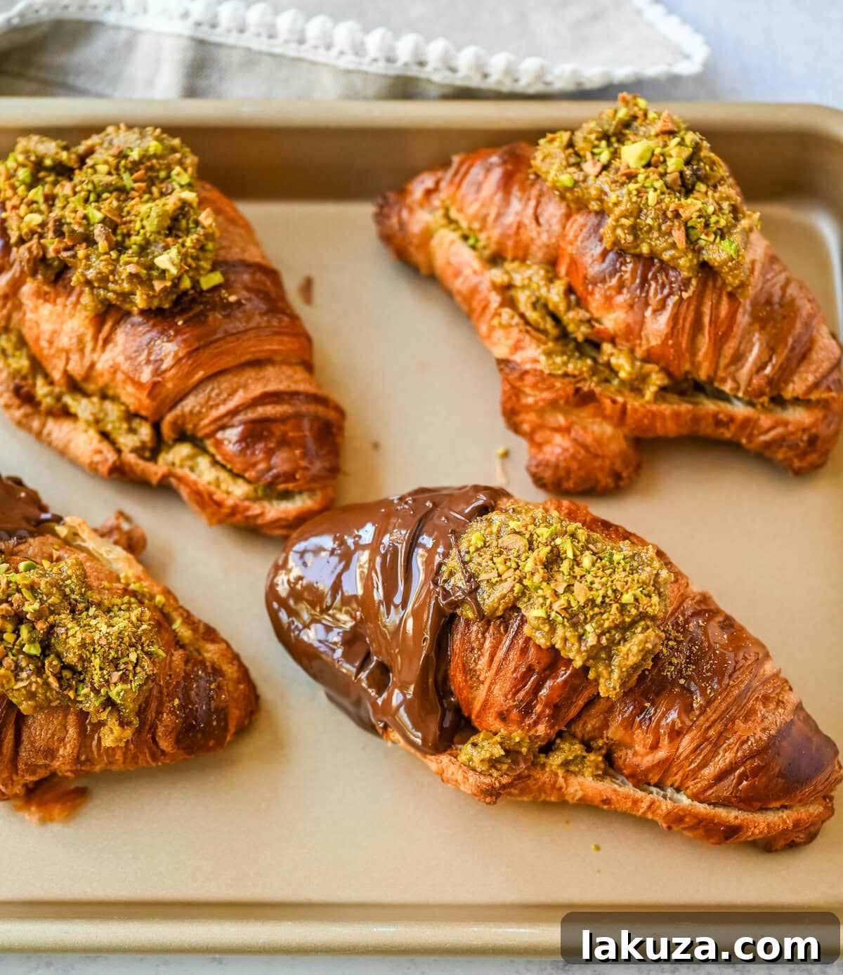 Make your own Pistachio Croissants dipped in chocolate at home in just a few easy steps! Buttery croissants are stuffed with a creamy pistachio cream filling and topped with a simple syrup and chopped pistachios for crunch. The easiest Pistachio chocolate Croissant recipe made in less than 30 minutes!
