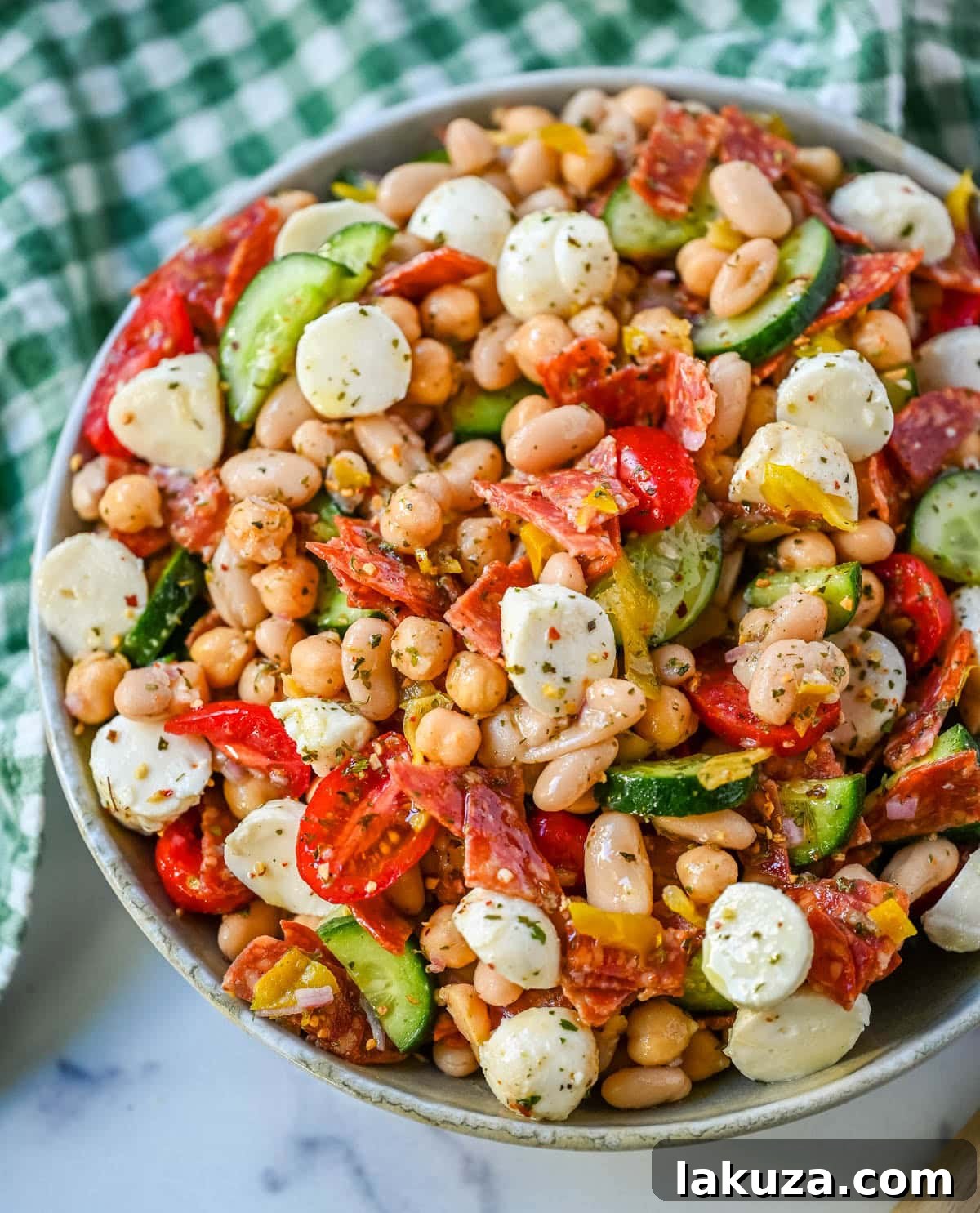 This Italian dense bean salad is the TikTok viral high protein meal prep recipe that has taken over the internet and for very good reason. Loaded with chickpeas, white beans, crisp Persian cucumbers, cherry tomatoes, creamy mozzarella, savory pepperoni or salami, and tangy pepperoncinis all tossed in a homemade Italian dressing, every single bite is packed with incredible flavor that gets better the longer it sits.