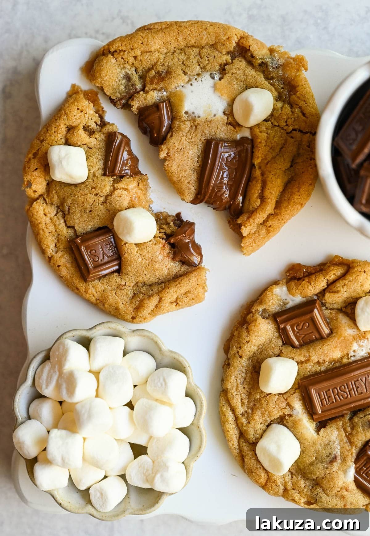 These homemade s'mores cookies are thick, soft, and chewy with gooey marshmallow bits and chopped Hershey bar throughout every bite. A full cup of finely crushed graham cracker crumbs goes straight into the dough, giving these cookies that unmistakable campfire s'mores flavor! This easy s'mores cookie recipe comes together in one bowl and is ready from start to finish in about 30 minutes.