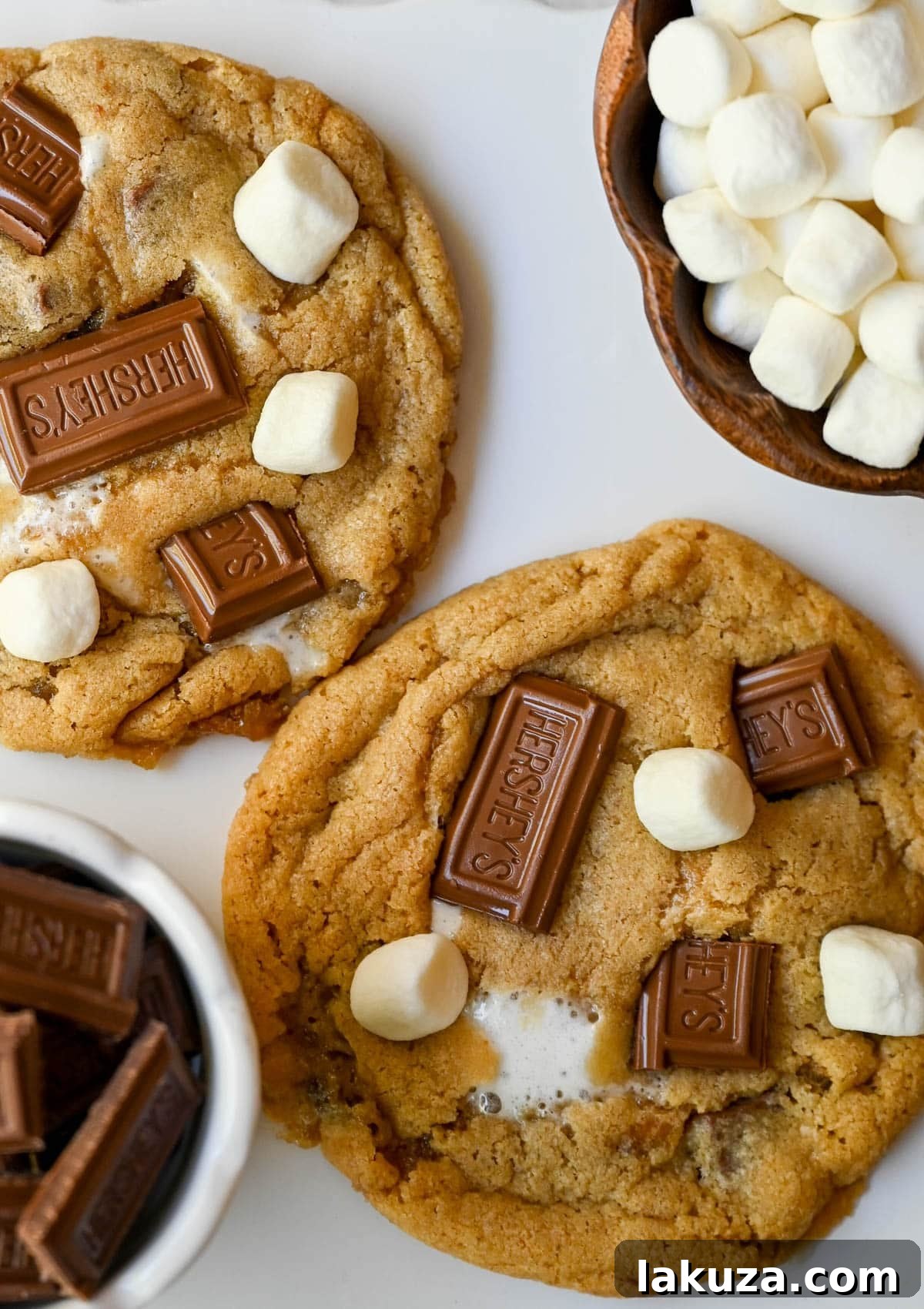 These homemade s'mores cookies are thick, soft, and chewy with gooey marshmallow bits and chopped Hershey bar throughout every bite. A full cup of finely crushed graham cracker crumbs goes straight into the dough, giving these cookies that unmistakable campfire s'mores flavor! This easy s'mores cookie recipe comes together in one bowl and is ready from start to finish in about 30 minutes.