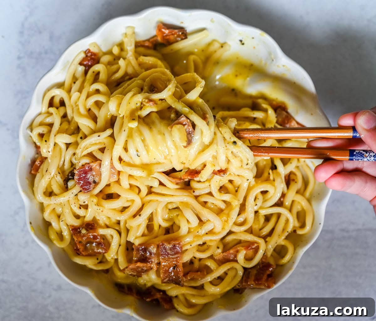 Japanese-Style Carbonara Udon with Bacon and Egg 4 Bowl of carbonara udon topped with egg yolk and black pepper.