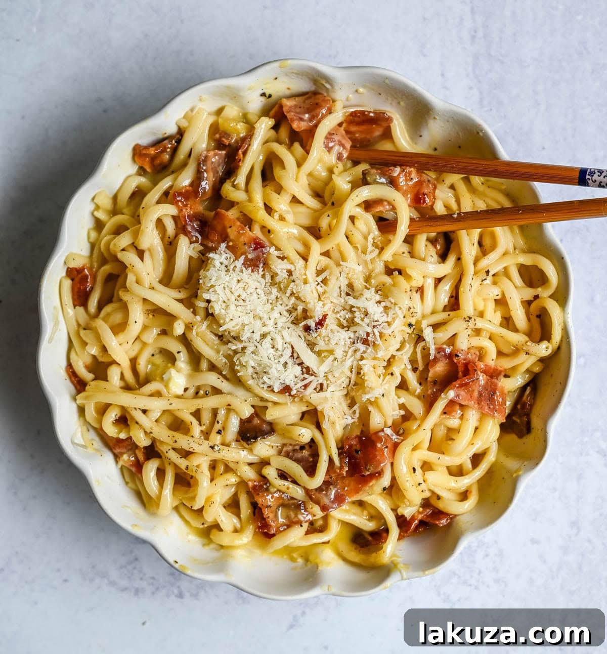 Japanese-Style Carbonara Udon with Bacon and Egg 5 Udon noodles in a pan with bacon and sauce.