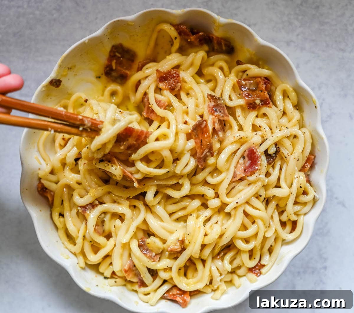 Japanese-Style Carbonara Udon with Bacon and Egg 6 Final plated carbonara udon topped with egg yolk and pepper.